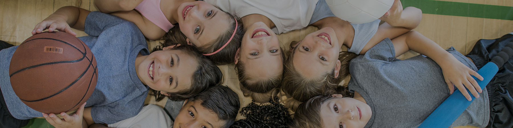 Group of young boys and girls with sports equipment, smiling at camera